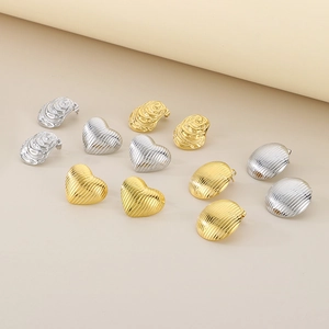 Dettaglio degli orecchini in oro 18K e argento con texture a cuore e ovali a rilievo