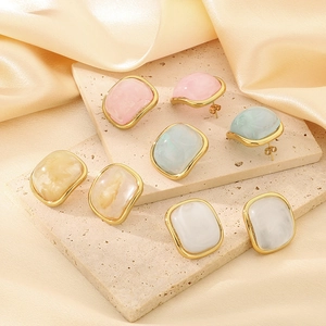 Boucles d'oreilles carrées en résine colorée et acier doré sur fond de soie champagne