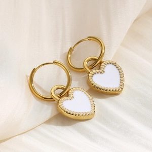 Elegant gold and white heart drop earrings displayed on a luxurious white silk background