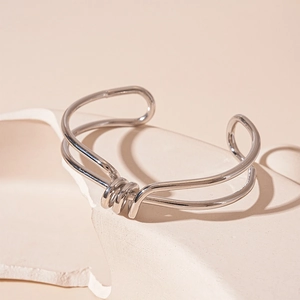 Detailed view of silver double-layered knotted cuff bracelet on artistic stone stand