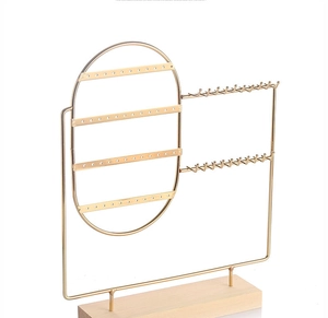 Detail of gold metal jewelry organizer with a solid wood base for earrings and necklaces