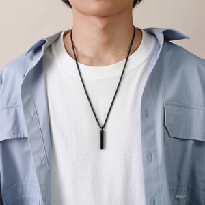 Detail view of a minimalist black rectangular tungsten pendant on a black cord necklace