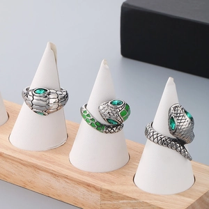 Three vintage silver snake rings with green rhinestone eyes on display stands