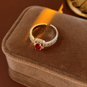 Macro shot of an adjustable silver ring with halo-set red oval gemstone on brown velvet