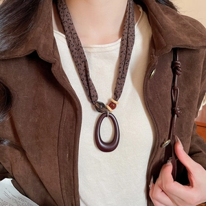 Close-up of leopard print fabric ethnic necklace with large oval resin pendant worn on a model