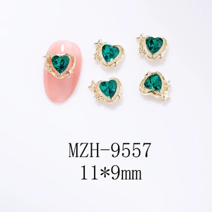 Bijou d'ongle cœur vert avec bordure dorée 11x9mm présenté sur un faux ongle rose