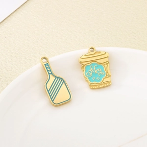Detail of creative blue enamel coffee cup and paddle charms on a white ceramic plate