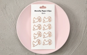 Set of 8 rose gold cat-shaped paper clips displayed on a pink ceramic plate