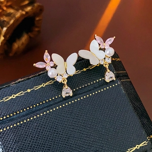 Boucles d'oreilles papillon avec zircon, perles et cristaux roses sur boîte à bijoux