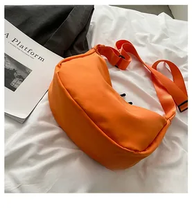 Detailed shot of an orange nylon dumpling bag with adjustable strap in casual setting