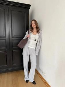 Detail of grey knitted polo cardigan and wide-leg trousers with premium textured finish