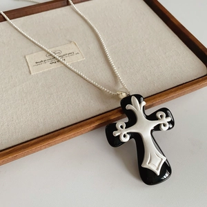 Detailansicht einer Kreuz-Halskette aus Harz auf einem hochwertigen Holz-Displaytablett