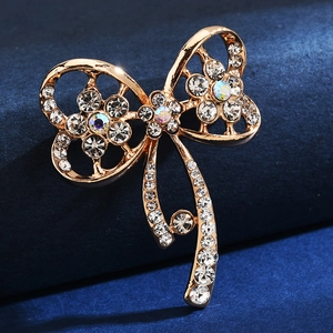 Elegant gold bow brooch featuring sparkling rhinestones on a premium blue velvet background