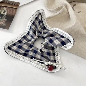 Detailed shot of blue checkered scrunchie with lace trim and red cherry pendant detail
