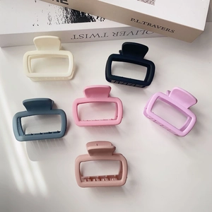 Flat lay of six matte square hair claws in assorted pastel colors on white surface