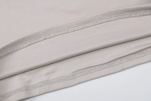 Dettaglio del tessuto a maglia grigio chiaro con doppia cucitura professionale sull'orlo