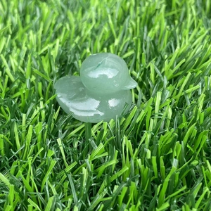 Macro shot of a small green aventurine gemstone duck carving on green grass