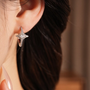 Close-up of silver star earrings with pavé zircons worn on ear for minimalist style