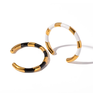 Titanium steel open bangles set in black, white, and gold enamel finish on white background