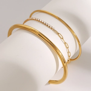 Dettaglio del set di tre bracciali dorati con zirconi su un supporto bianco elegante