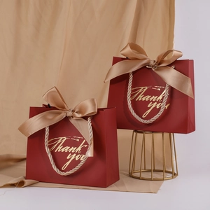 Detail of red wedding gift bags with golden rope handles and bow tie decorations