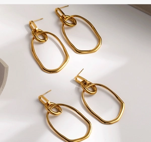 Detail of gold geometric earrings with layered oval and rectangular hollow hoops