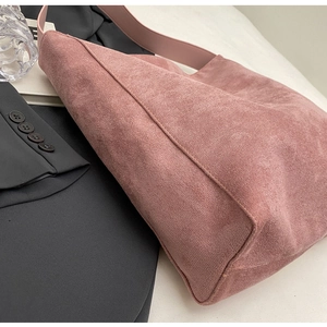 Detail der altrosa Wildleder-Einkaufstasche mit Lederriemen auf Büro-Blazer Hintergrund