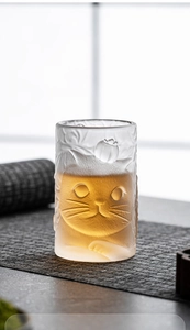 Close-up of a cute cat-shaped frosted glass tea cup with warm liquid inside
