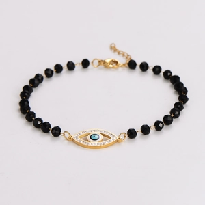 Detail of black faceted bead bracelet with golden evil eye charm and lobster clasp