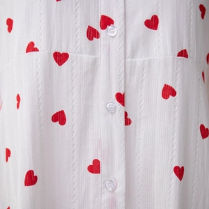 Détail de la robe blanche à imprimé cœurs avec texture dentelle et boutons clairs
