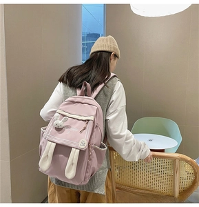 Detail of pink cartoon backpack featuring cute bunny ears and a soft plush rabbit charm