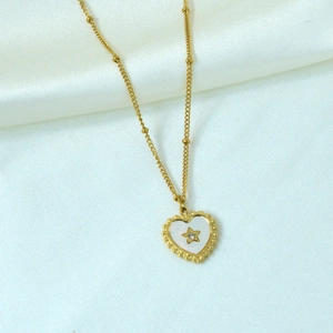 Macro view of gold heart pendant necklace with white inlay and star crystal detail