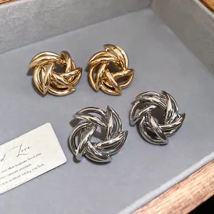 Elegant gold and silver twisted spiral stud earrings on a grey velvet display