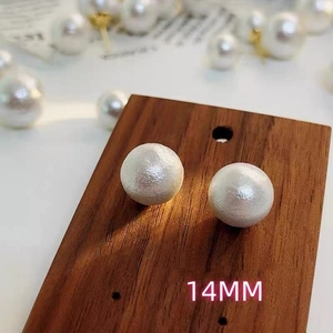 Macro detail of 14mm matte cotton pearl stud earrings with textured vintage finish