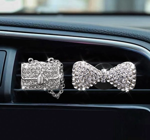 Sparkling rhinestone handbag and bow car air vent clips on a dashboard interior