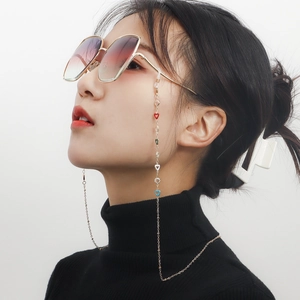 Golden eyewear chain with colorful enamel hearts worn by a model on a black sweater