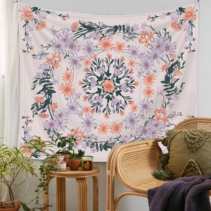 Bohemian floral mandala tapestry in orange and purple tones hanging on a cozy wall