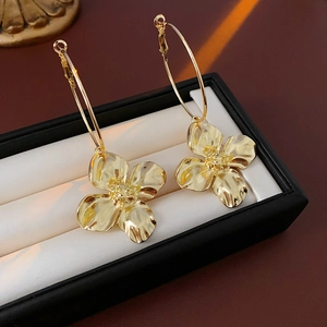 Detailed macro view of gold metallic flower hoop earrings on a luxury jewelry box