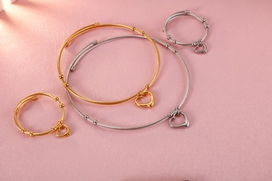 Detailed top view of gold and silver steel wire heart necklaces and bracelet set on pink background