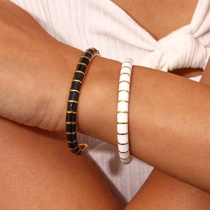 Detail of 18K gold plated bangle with black and white enamel drip on a woman's wrist