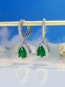 Macro shot of silver drop earrings with pear-cut green crystals and sparkling stones