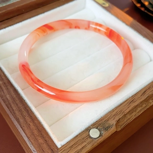 Detailed macro view of polished red agate circle bangle on a luxury jewelry display box