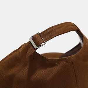 Detail of adjustable metal buckle and thick canvas strap on a brown baseball cap
