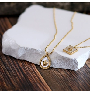 Detailed close-up of 18K gold plated necklaces with teardrop crown and flower shell pendants