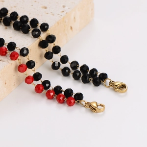 Faceted black and red beaded bracelet set with gold lobster clasp on stone stand