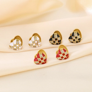 Detailed view of heart-shaped checkerboard earrings with rhinestones on silk