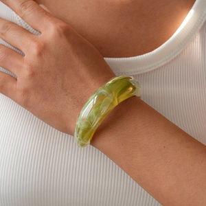 Detail of green marble resin bangle showing smooth texture on woman's wrist