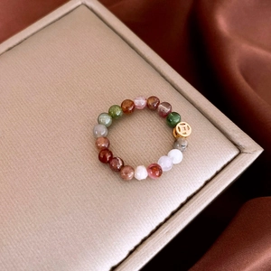 Macro detail of multicolored beaded ring with vintage gold coin charm on silk