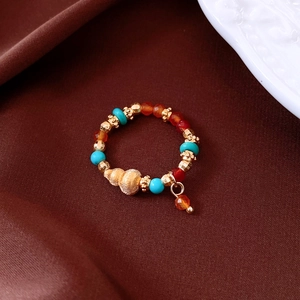 Close-up of vintage beaded ring with tiger eye, agate, and gold conch shell charm