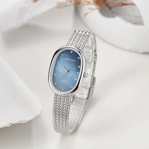 Detailed macro of oval blue mother-of-pearl watch dial with rhinestone markers
